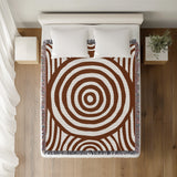 Alaka Circles Cotton Throw Blanket in Rust Brown, on a bed