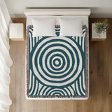 Alaka Circles Cotton Throw Blanket in Teal, on a bed