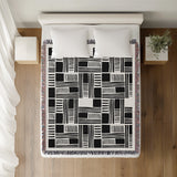 Anala Abstract Cotton Throw Blanket in Black, on a bed
