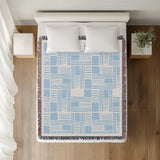 Anala Abstract Cotton Throw Blanket in Sky, on a bed