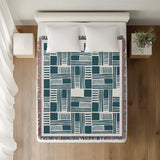 Anala Abstract Cotton Throw Blanket in Teal, on a bed