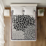 Arlo Floral Burst Cotton Throw Blanket in Black, on a bed