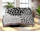 Arlo Floral Burst Cotton Throw Blanket in Black, draped over a sofa