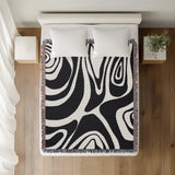 Binitie Zebra Print Cotton Throw Blanket in Black, on a bed