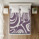 Binitie Zebra Print Cotton Throw Blanket in Purple, on a bed