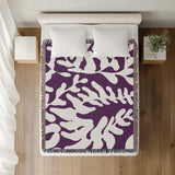 Booker Floral Cotton Throw Blanket in Purple, on a bed