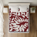 Booker Floral Cotton Throw Blanket in Red, on a bed