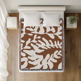 Booker Floral Cotton Throw Blanket in Rust Brown, on a bed