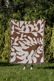 Booker Floral Cotton Throw Blanket in Rust Brown, outdoors