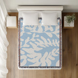 Booker Floral Cotton Throw Blanket in Sky, on a bed