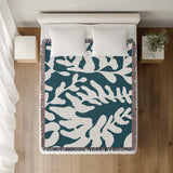 Booker Floral Cotton Throw Blanket in Teal, on a bed