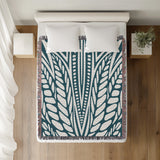 Buga Abstract Print Cotton Throw Blanket in Teal, on a bed
