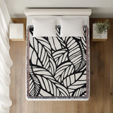 Caro Floral Cotton Throw Blanket in Black, on a bed