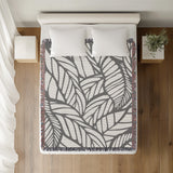 Caro Floral Cotton Throw Blanket in Gray, on a bed