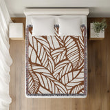 Caro Floral Cotton Throw Blanket in Rust Brown, on a bed