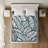 Caro Floral Cotton Throw Blanket in Teal, on a bed