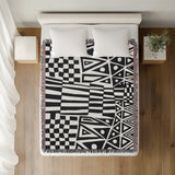 Cocodili Abstract Print Cotton Throw Blanket in Black, on a bed