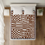 Cocodili Abstract Print Cotton Throw Blanket in Rust Brown, on a bed