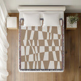 Colette Checkered Cotton Throw Blanket in Beige, on a bed
