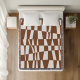 Colette Checkered Cotton Throw Blanket in Rust Brown, on a bed