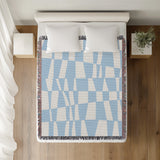 Colette Checkered Cotton Throw Blanket in Sky, on a bed