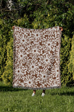 Dandelion Floral Cotton Throw Blanket in Rust Brown, outdoors