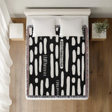 Deka Abstract Cotton Throw Blanket in Black, on a bed