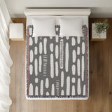 Deka Abstract Cotton Throw Blanket in Gray, on a bed