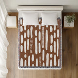 Deka Abstract Cotton Throw Blanket in Rust Brown, on a bed