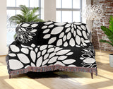 Fiesta Floral Cotton Throw Blanket in Black, draped over a sofa