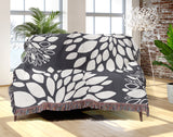 Fiesta Floral Cotton Throw Blanket in Gray, draped over a sofa