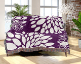Fiesta Floral Cotton Throw Blanket in Purple, draped over a sofa
