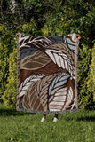 Gabo Floral Cotton Throw Blanket in Beige, draped over a sofa