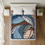 Gabo Floral Cotton Throw Blanket in Blue, on a bed