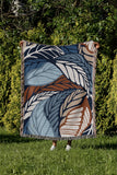 Gabo Floral Cotton Throw Blanket in Blue, draped over a sofa