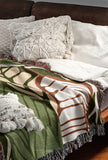 Gabo Floral Cotton Throw Blanket in Green, draped over a sofa