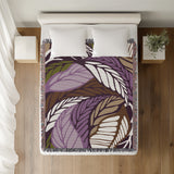 Gabo Floral Cotton Throw Blanket in Purple, on a bed