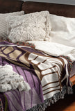 Gabo Floral Cotton Throw Blanket in Purple, draped over a sofa