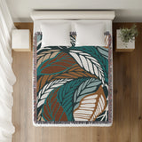 Gabo Floral Cotton Throw Blanket in Turquoise, on a bed