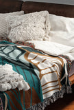 Gabo Floral Cotton Throw Blanket in Turquoise, draped over a sofa