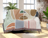 Ira Abstract Face Cotton Throw Blanket, draped over a sofa