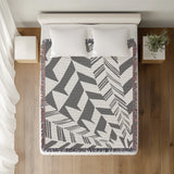 Kafi Abstract Cotton Throw Blanket in Gray, on a bed