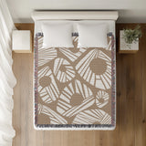 Kio Abstract Print Cotton Throw Blanket in Beige, on a bed