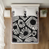 Kio Abstract Print Cotton Throw Blanket in Black, on a bed
