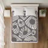 Kio Abstract Print Cotton Throw Blanket in Gray, on a bed