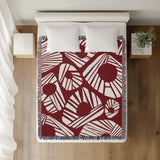 Kio Abstract Print Cotton Throw Blanket in Red, on a bed