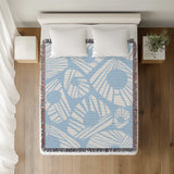Kio Abstract Print Cotton Throw Blanket in Sky, on a bed
