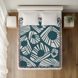 Kio Abstract Print Cotton Throw Blanket in Teal, on a bed
