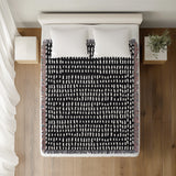 Kola Abstract Print Cotton Throw Blanket in Black, on a bed