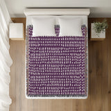 Kola Abstract Print Cotton Throw Blanket in Purple, on a bed
